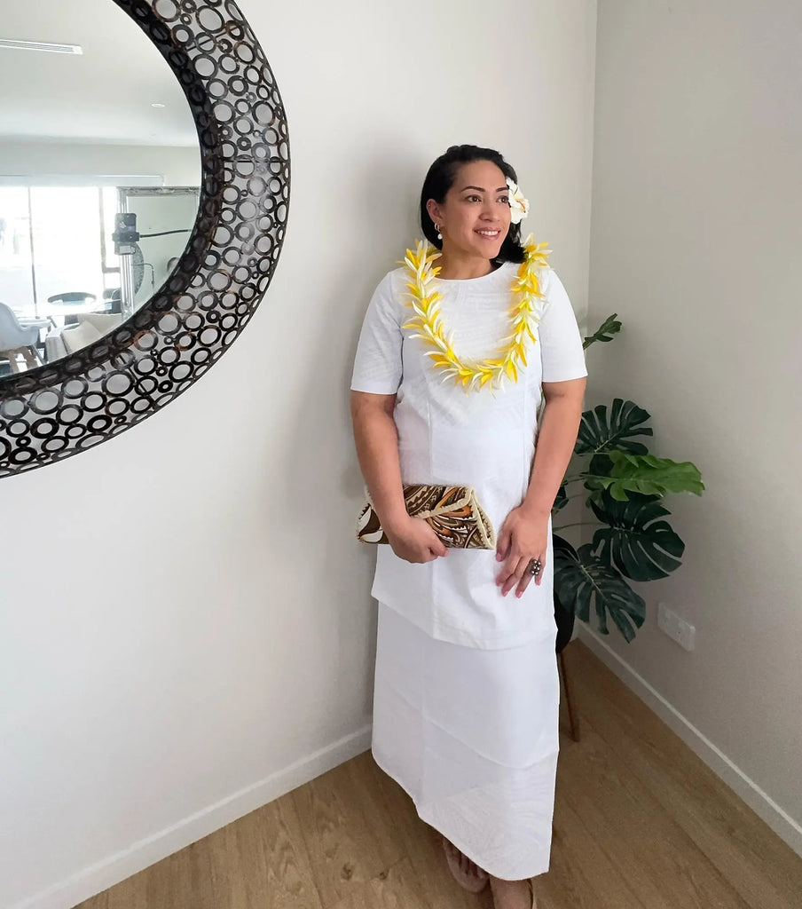 Model in a white puletasi with Pacific patterns, showcasing its modest fit and cultural elegance.