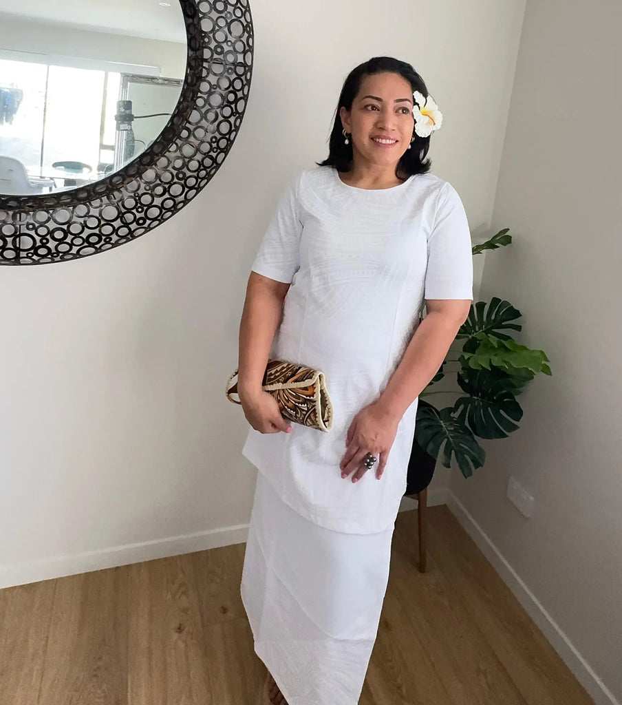 Model in a white puletasi with Pacific patterns, showcasing its modest fit and cultural elegance.